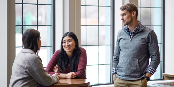 Three young people converse at a small round table