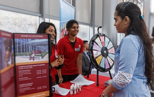 Two nursing students talk to a girl at a career event.
