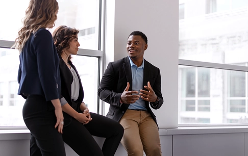 A group of young professionals have a conversation in a hallway