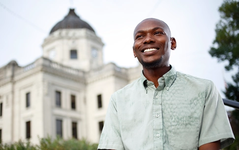 A man stands smiling outside of a courthouse