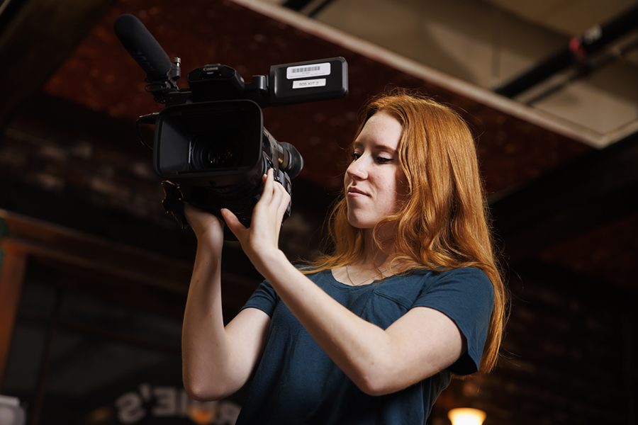 A female student looks through the lens of a video camera.