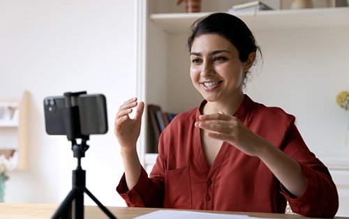 A female student smiles as she adjusts a phone on a tripod.