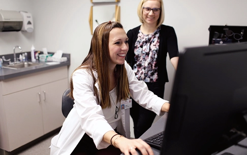 A doctor and colleague review information on a computer