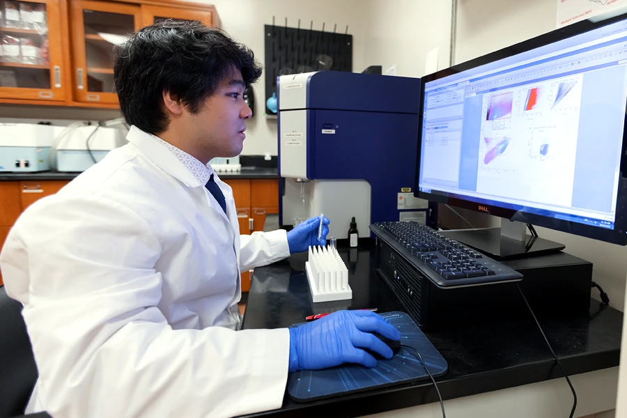 A man in a white coat reviews data on a computer