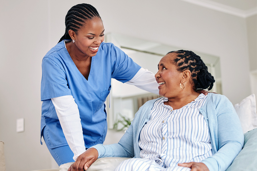 A healthcare worker has a lively conversation with an elderly patient.