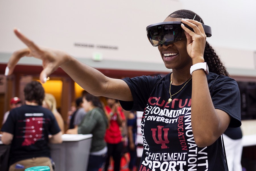 A female student points in the air while looking through virtual reality goggles.