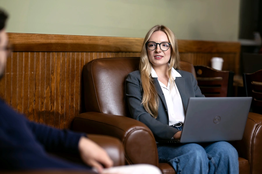 A woman talks with a colleague while holding a laptop