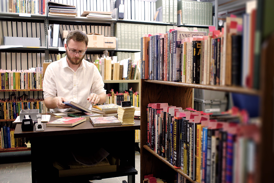 A library worker organizes books at a desk.