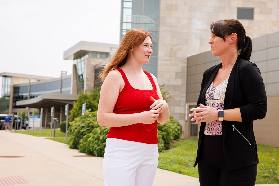 Two colleagues have a discussion outside a hospital building.