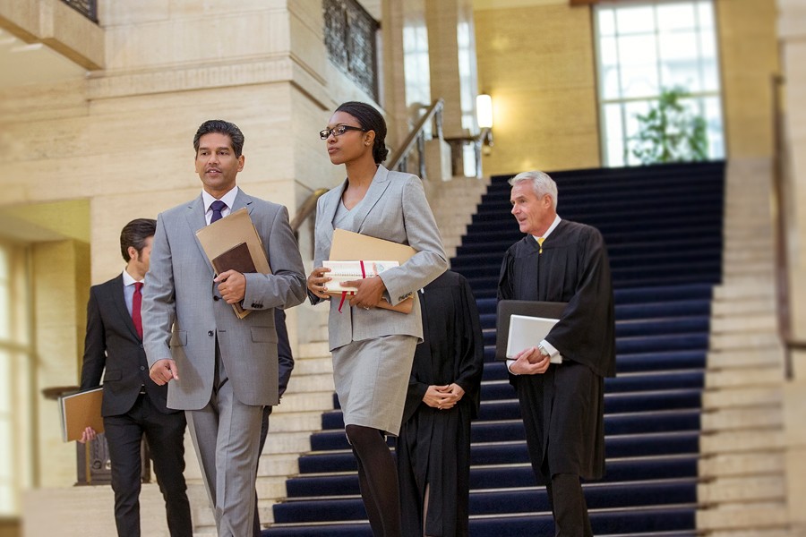 A group of professionals in suites walk through a stately building.