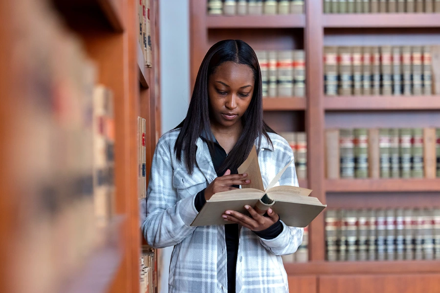 A woman looks through a book in a law school library.