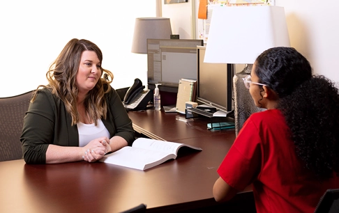 An advisor speaks with a student in an office