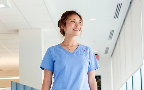 A woman in scrubs walks down a hallway