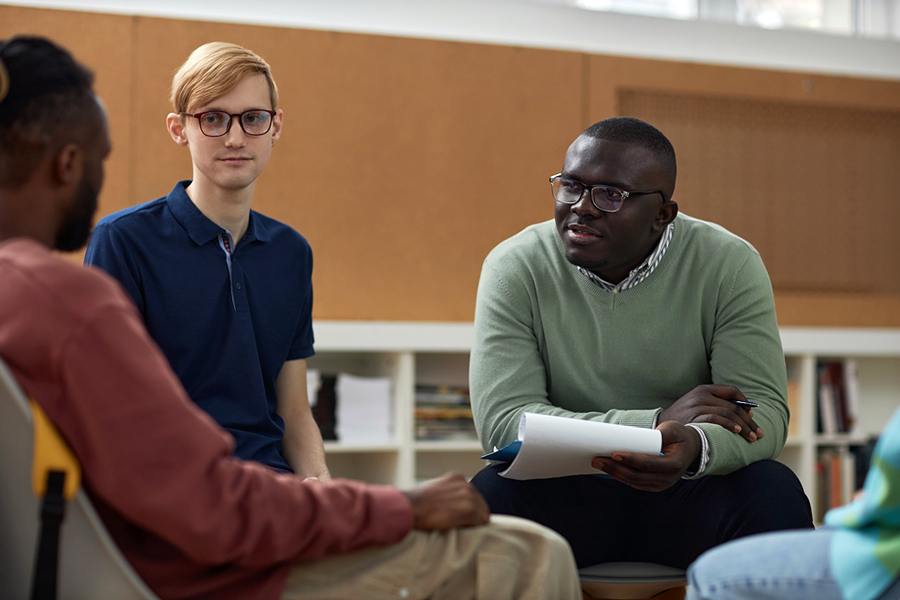 A psychologist sits with a group of students having a discussion.