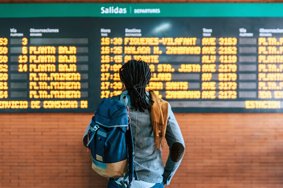 A woman stands with her back to the camera while looking at a bus schedule written in Spanish.