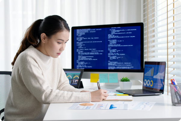 Person working on data analysis on a notepad with a computer in the background